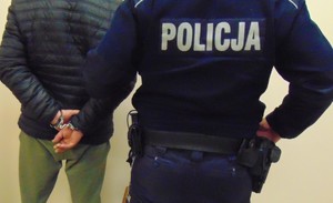 Policjant z zatrzymanym stoją przy ścianie