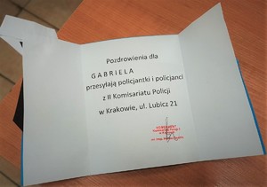 Kartka z pozdrowieniami od policjantów Komisariatu wraz z pieczęcią i podpisem Komendanta.