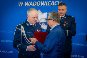 Na zdjęciu Komendant Powiatowy Policji w Wadowicach w umundurowaniu galowym odbierający podziekowania za współpracę od Starosty Wadowickiego. W tle Komendant Wojewódzki Policji w Krakowie