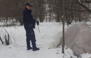 policjant podczas kontroli namiotu rozbitego w zagajniku leśnym
