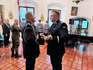 komendant wojewódzki policji w Krakowie wręczający szablę odchodzącemu komendantowi