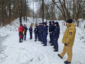 Policjanci stoja w szeregu przed ratownikiem GOPR. W tle krajobraz zimowy