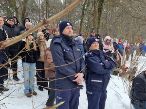 Policjantka i policjant na tle zgromadznych uczestników pokazu ratowania osoby tonącej spod lodu
