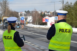 Policjantka oraz policjant ruchu drogowego stoją nieopodal przejścia dla pieszych i nadzorują ruch