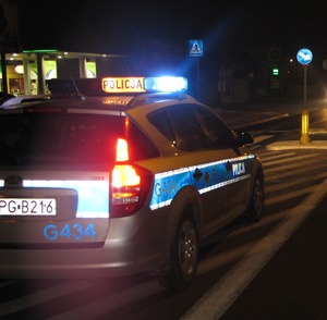radiowóz jadący ulicą na sygnałach  w nocy