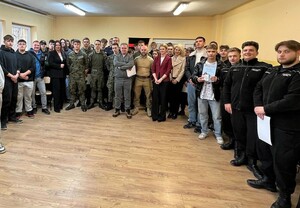 Grupa osób stojaca przodem. Część osób w strojach cywilnych, część w mundurach.