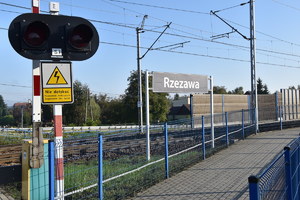 Przejazd kolejowy w Rzezawie. Sygnalizator świetlny oraz tablica z napisem Rzezawa