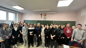 umundurowany policjant wspólnie z uczniami klasy policyjnej w szkole średniej