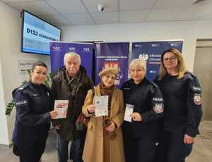 mężczyzna i kobieta trzymając ulotki pozuje do wspólnego zdjęcia z policjantkami