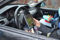 na zdjęcie wnętrze pojazdu, kierujący trzyma w ręku tablet i ogląda wyświetlany materiał filmowy.
