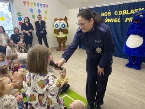 policjantka trzymająca mikrofon dziewczynce odpowiadającej na zadane pytania
