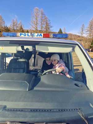dziewczynka i chłopczyk siedzący za kierownica policyyjnego radiowozu