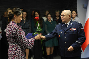komendant przekazuje kolejnej pracownicy oficjalne życzenia i podaje różę