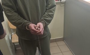 Mężczyzna stoi w kajdankach założonych na ręce z przodu