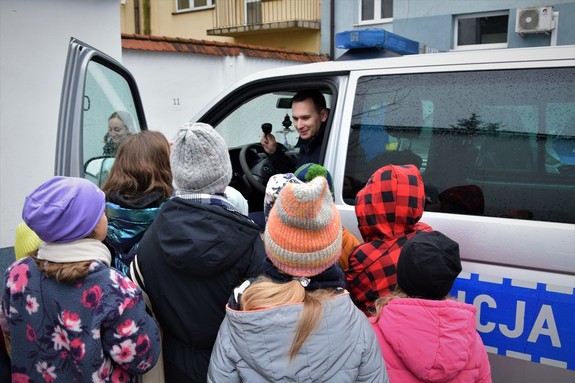 młodszy aspirant Sebastian Kruk w policyjnym radiowozie otoczony dziećmi podczas spotkania