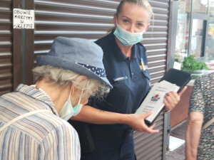 policjantka wręcza starszej kobiecie ulotkę informacyjną
