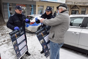 Policjanci Wydziału Prewencji KMP w Krakowie wręczający kalendarz przechodniowi na pętli tramwajowej.