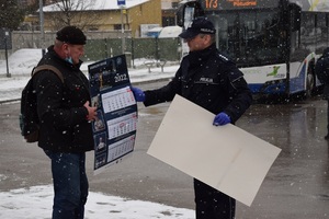Policjant prewencji wręczający kalendarz mężczyźnie znajdującemu się na zajezdni autobusowej.