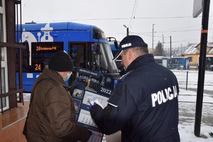 Policjant wręczający kalendarz seniorce na zajezdni tramwajowej.